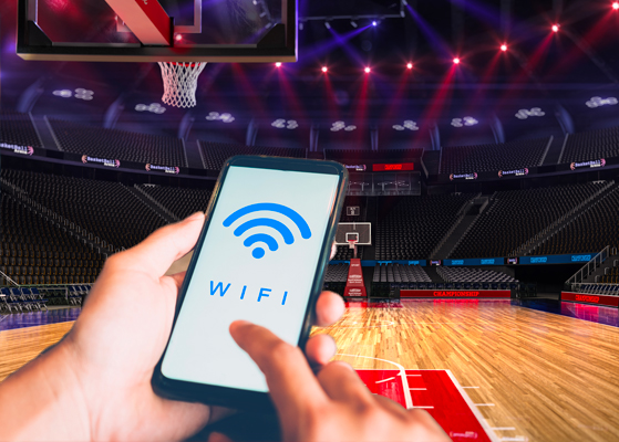 Stock image of a person choosing wifi option on their cell phone at a basketball stadium